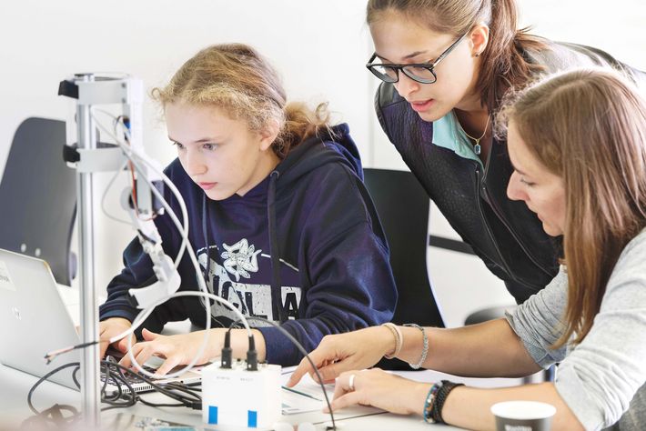 Foto der Schülerin Mina und ihrer Mentorin Stefanie Burri (Bauingenieurin) beim Programmieren eines Roboterarms.