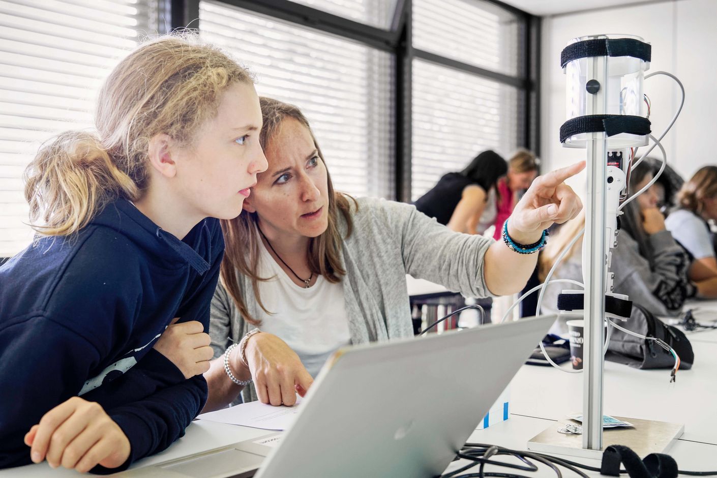 Foto der Schülerin Mina und ihrer Mentorin Stefanie Burri (Bauingenieurin) beim Programmieren eines Roboterarms.