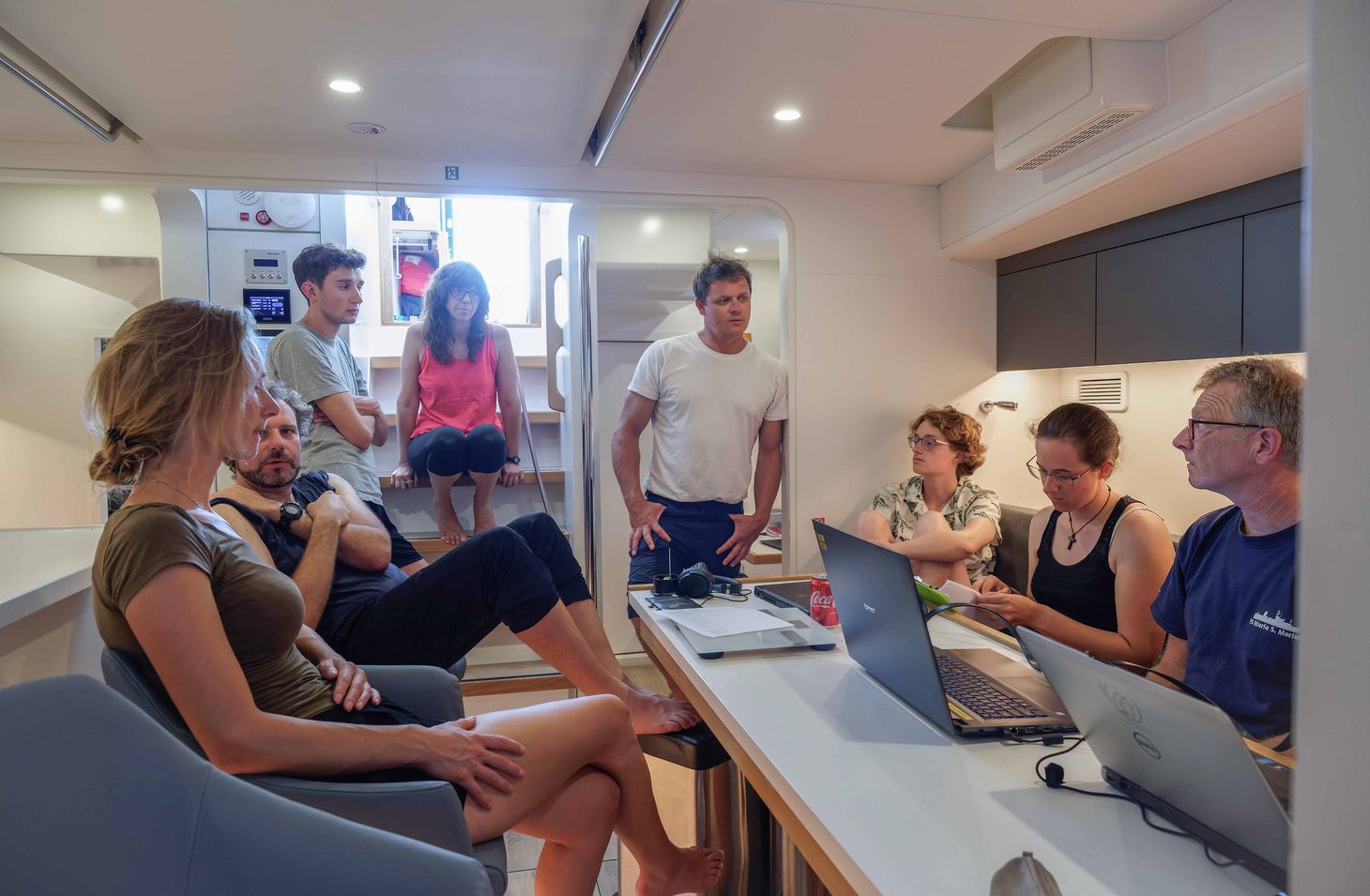 Crew, interns and scientists at a meeting. What have we accomplished, and what do we do next? How will the winds and currents change?